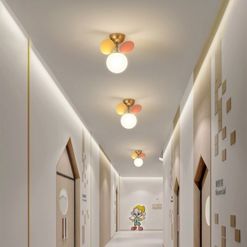 Three separate single-globe Jevon colourful petal lights along a hallway with a cartoon mural at the far end.