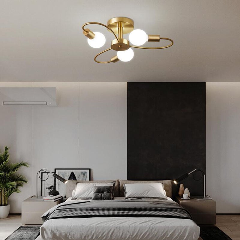 Valentina Gold three-light option above a monochrome bedroom with a dark panel, grey bedding and separate bedside lamps.