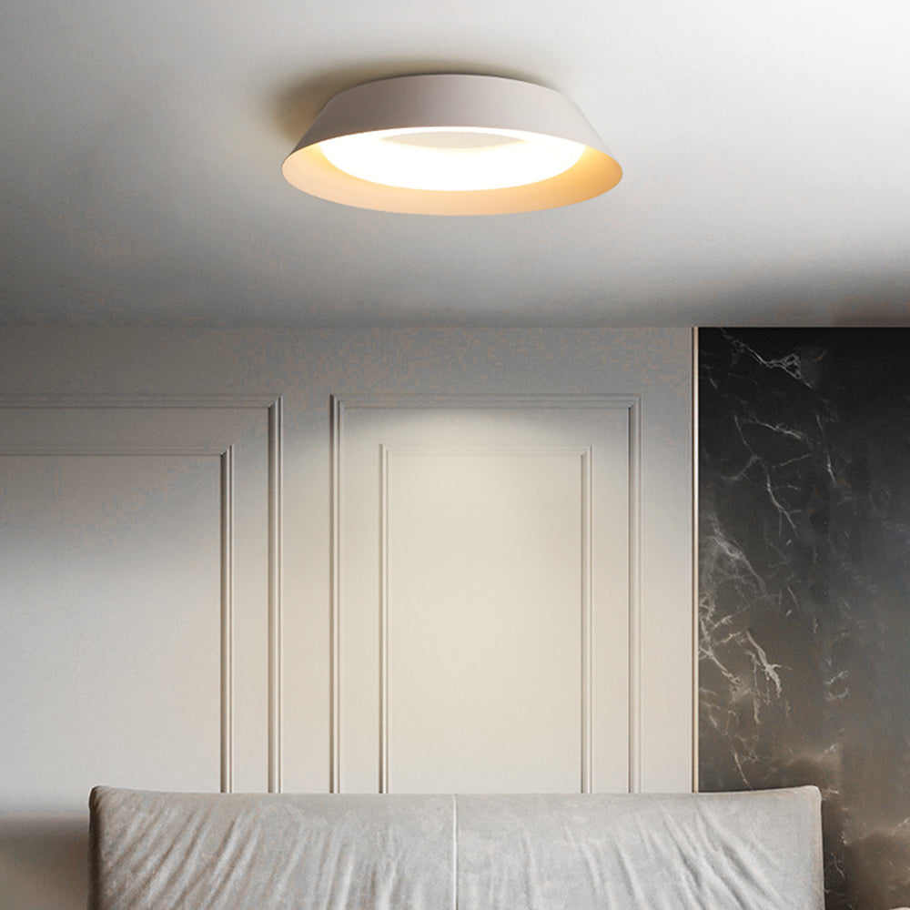 Quinn lit white bowl ceiling light above pale upholstery, decorative wall mouldings and a dark marble-like panel.