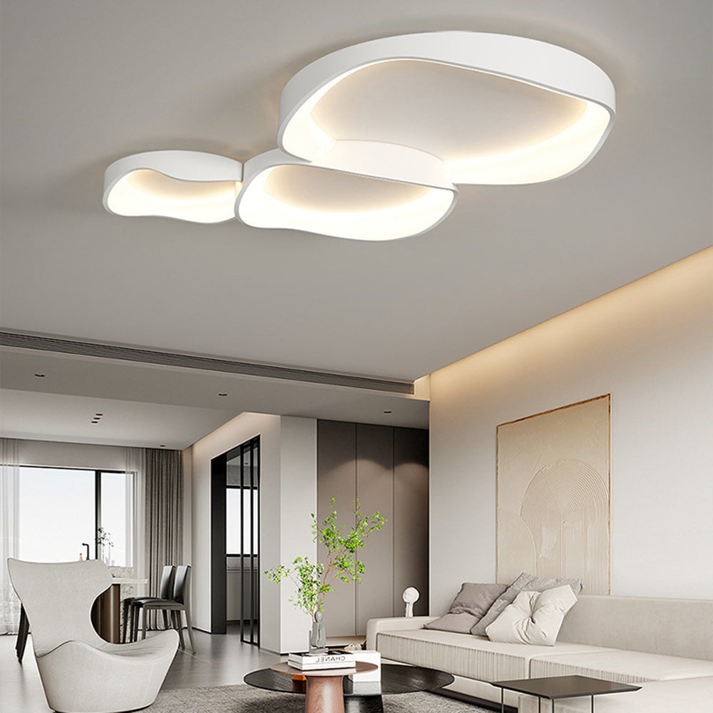 Three-bowl Arisha light over cream sofa and black tables, with green branches, white sculptural chair and pale circular wall art.