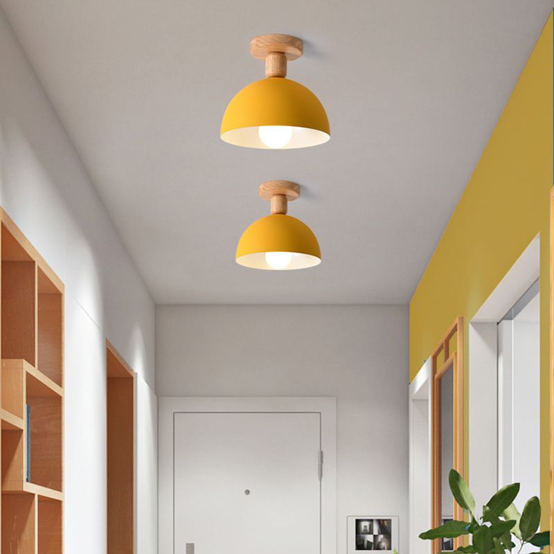 Two yellow Ozawa Dome ceiling lights in hallway with yellow wall, wood-framed mirror, plant, cubby shelves and white entry door
