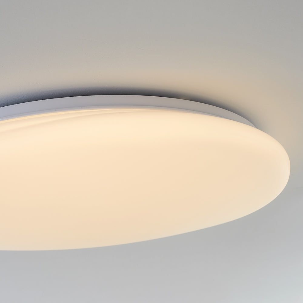 Oblique close-up of Quinn rounded diffuser edge, pale housing rim and side screw beneath the ceiling.