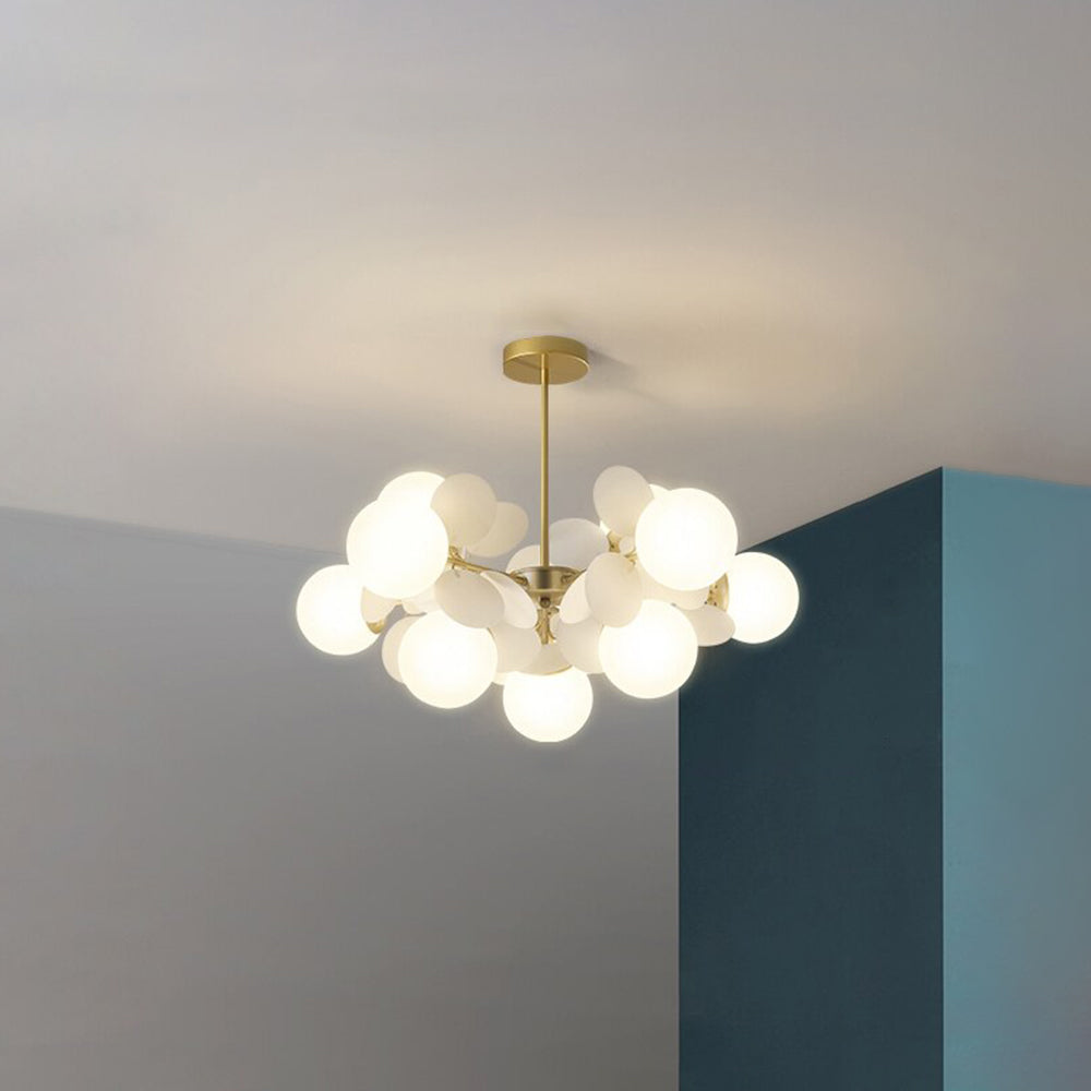 Jevon White 26.3-inch 10-light option with pale oval petals and white globes around gold-tone branches by a teal wall.