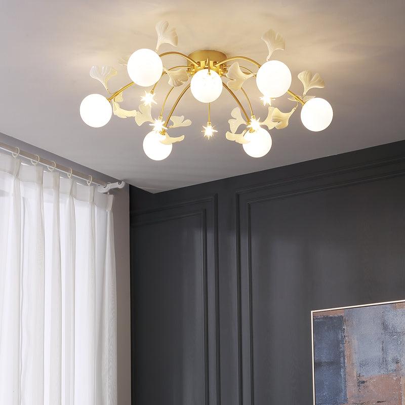Olivia with seven lit white globes, pale leaf ornaments and small stars above a dark gray panelled wall, white curtains and abstract art.