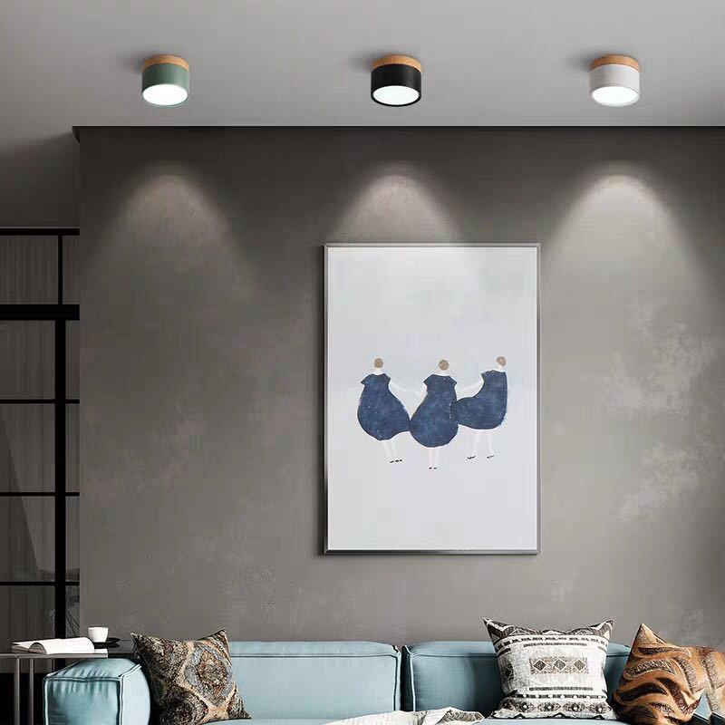 Green, black and white Morandi cylinders above blue framed art, a pale-blue sofa, patterned cushions and open shelves.