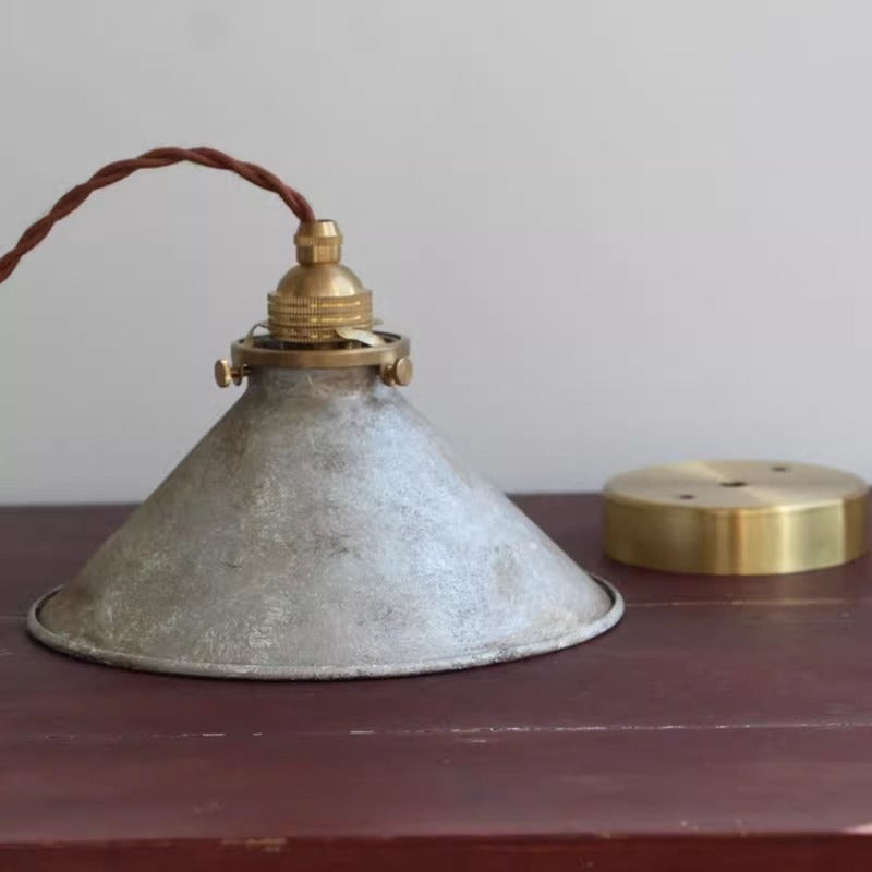 Silver Alessio shade on a wood tabletop, with mottled finish, gold-coloured top fitting, brown cord and a separate round canopy.
