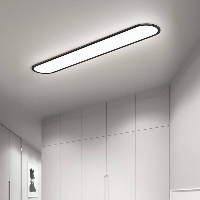 Black Edge ceiling light above gray wardrobe panels with slim vertical handles, beside a mirror and monochrome artwork.
