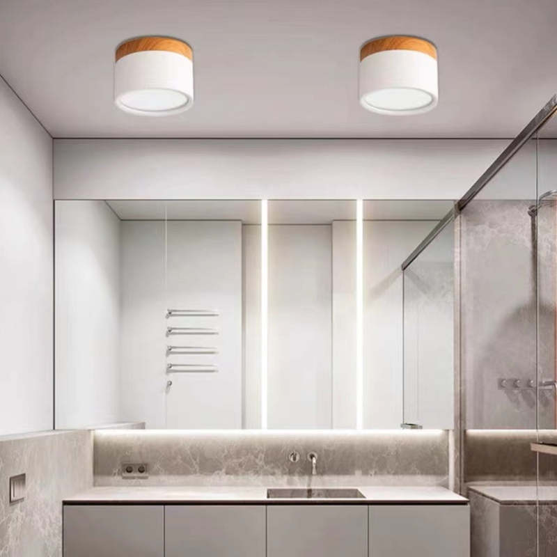 Two white Morandi cylinders pictured above a bathroom vanity, mirror, gray walls and glass shower enclosure.