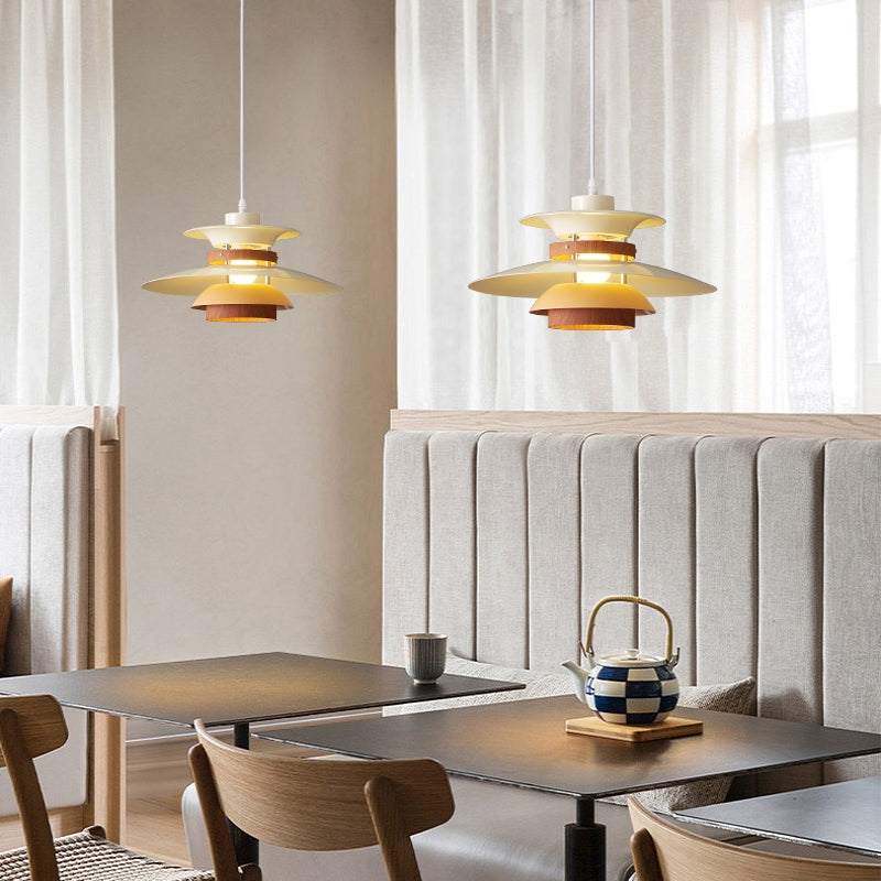Two glowing cream layered pendants with wood-grain bands above restaurant tables beside a padded booth and curtains
