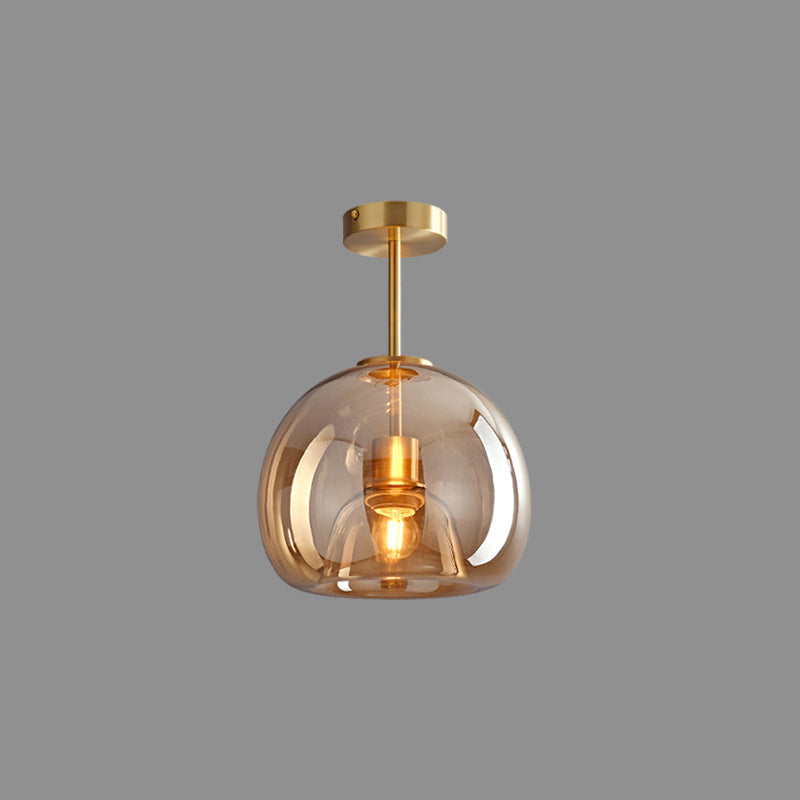 Gold Sanna long-stem light isolated on grey background with rigid stem, round canopy, glass dome and central bulb.