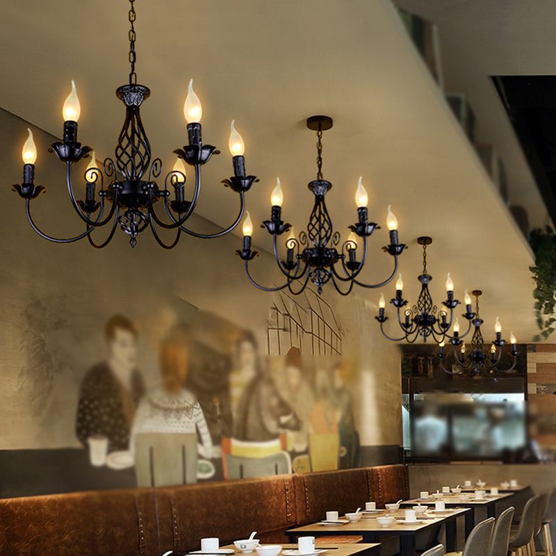 Several black Silva six-light chandeliers above restaurant tables and wall mural, with curved candle arms and chain suspension