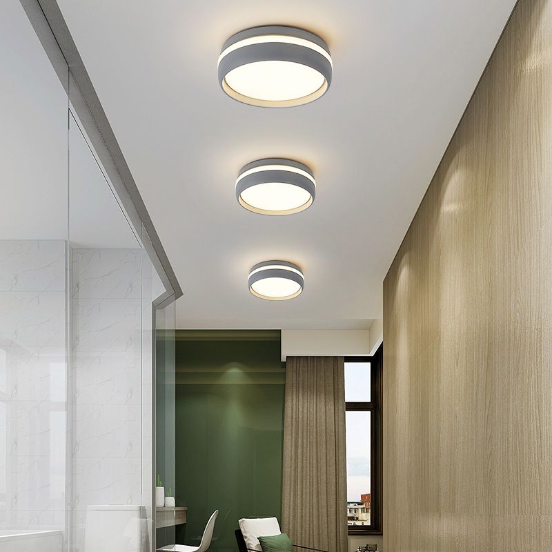 Three grey round ceiling lights along a hallway ceiling beside a wooden wall and glazed partition