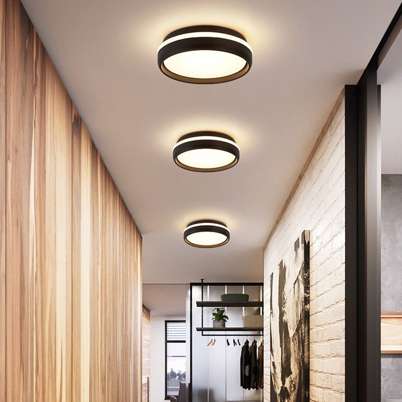 Three black round ceiling lights along a passage with wood paneling, pale brick wall and coat rail