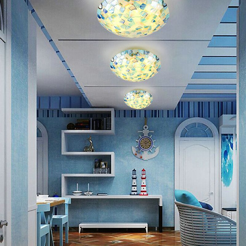 Three illuminated Morandi shell-mosaic ceiling lights in a blue-toned room with shelves and chairs.