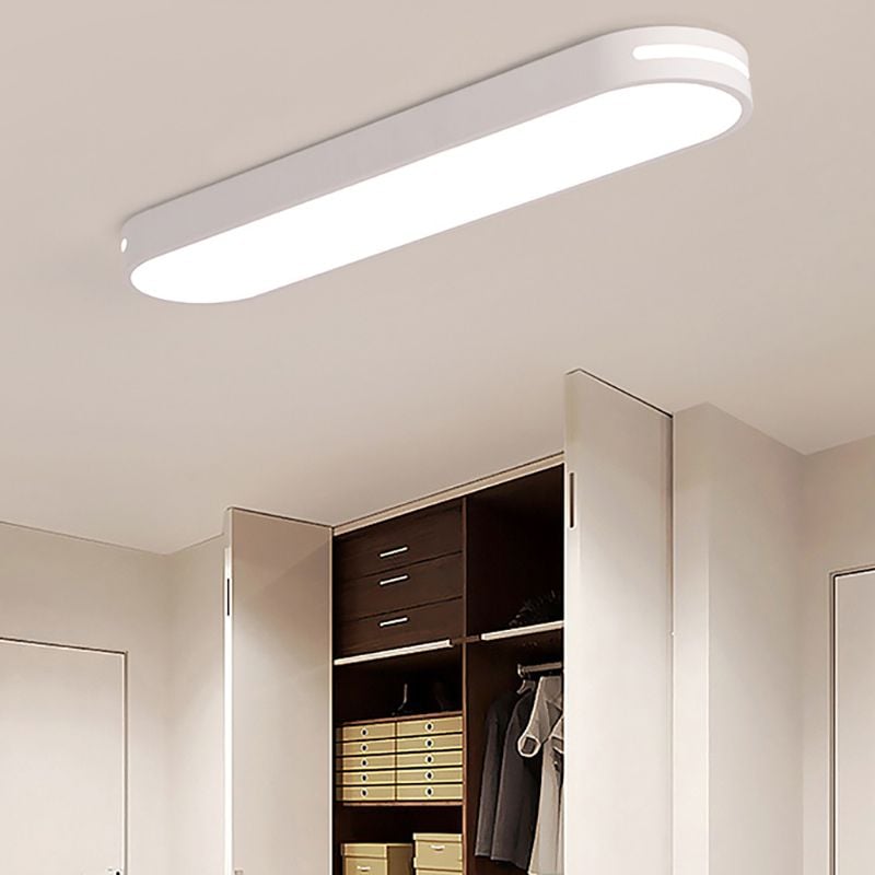 White Quinn ceiling light with a bright slot near the rounded end above an open wardrobe with dark drawers and yellow storage boxes.