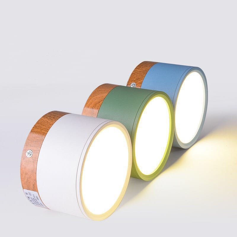 Angled view of white, green and blue Morandi cylinders with wood-look bands, pale circular faces and side screws.
