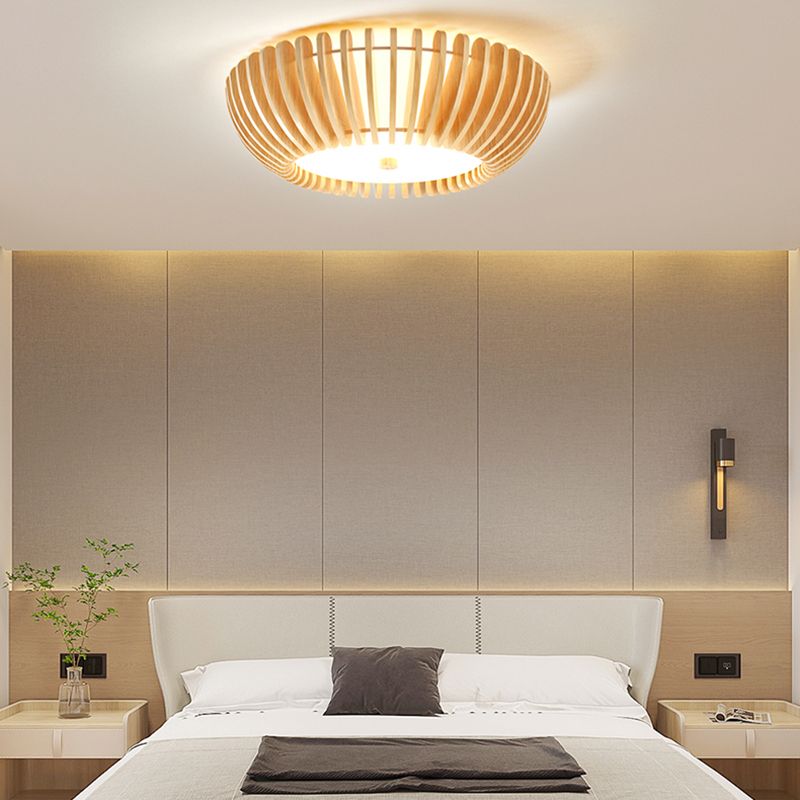 Lit Ozawa wood-slatted ceiling fixture above a gray-and-beige headboard and dark cushion, with a plant and separate vertical wall light.