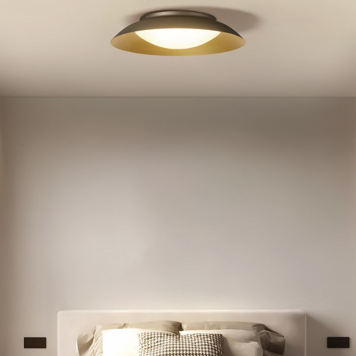 Carins round ceiling light above a pale headboard and houndstooth cushion, with small dark wall fittings.
