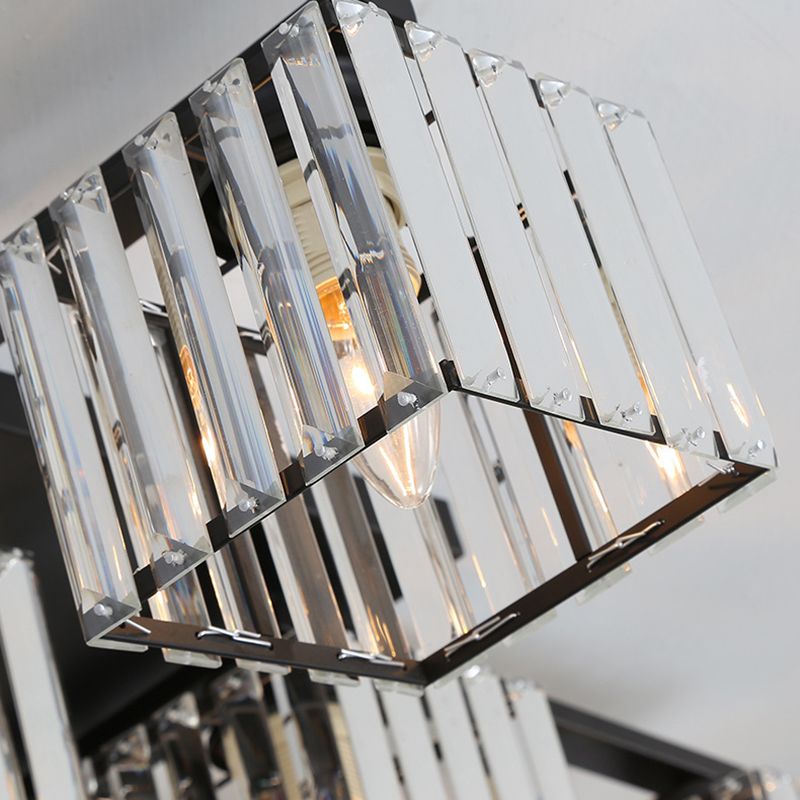 Close-up of a black Kristy cube shade with clear faceted-looking vertical strips, attachment tabs and a lit example bulb behind.