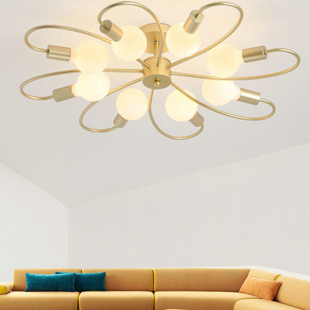 Valentina Gold eight-loop light above a mustard sofa with teal and orange cushions in a pale living room.