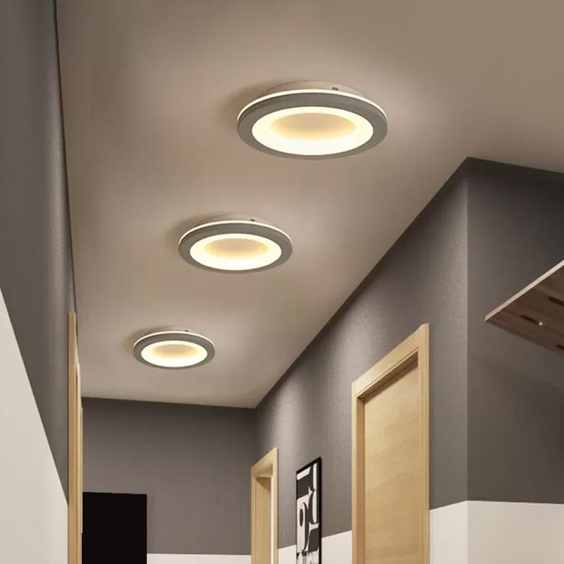 Three circular gray fixtures with yellow-lit rings along an indoor hallway ceiling