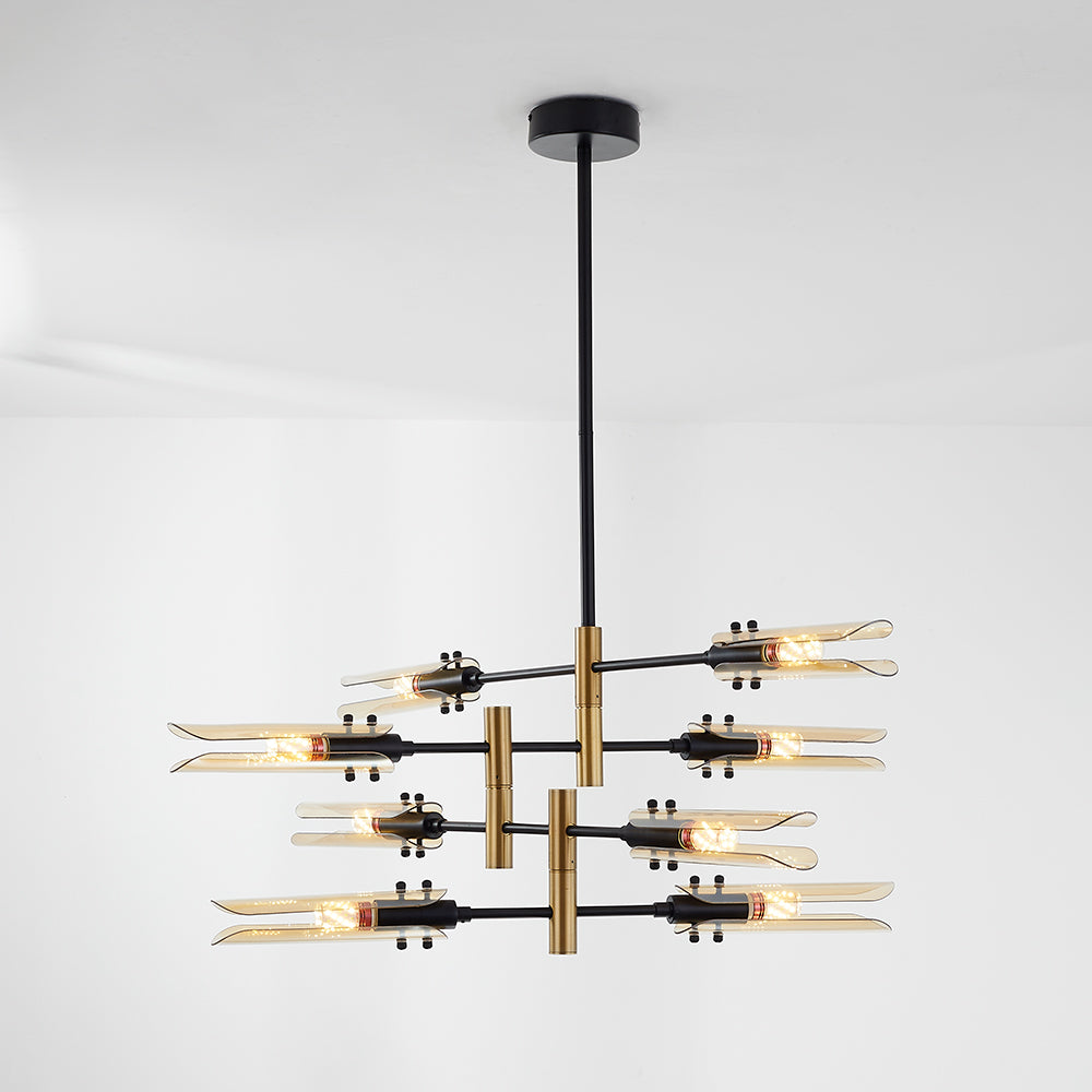 Amber Sanna eight-head light against a pale wall, with four crossed black bars, gold-tone joints and a rigid black stem.