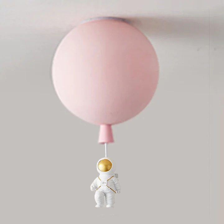 Pale pink balloon globe at the ceiling with a seated white astronaut and gold-tone visor beneath a pale link.