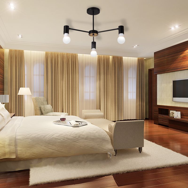 Black three-light ceiling fixture above a bedroom with bed, armchairs, curtains and wall-mounted television
