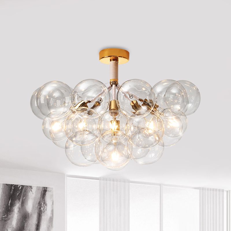 Gold-tone six-light clear globe ceiling fixture near a window, curtains and abstract artwork