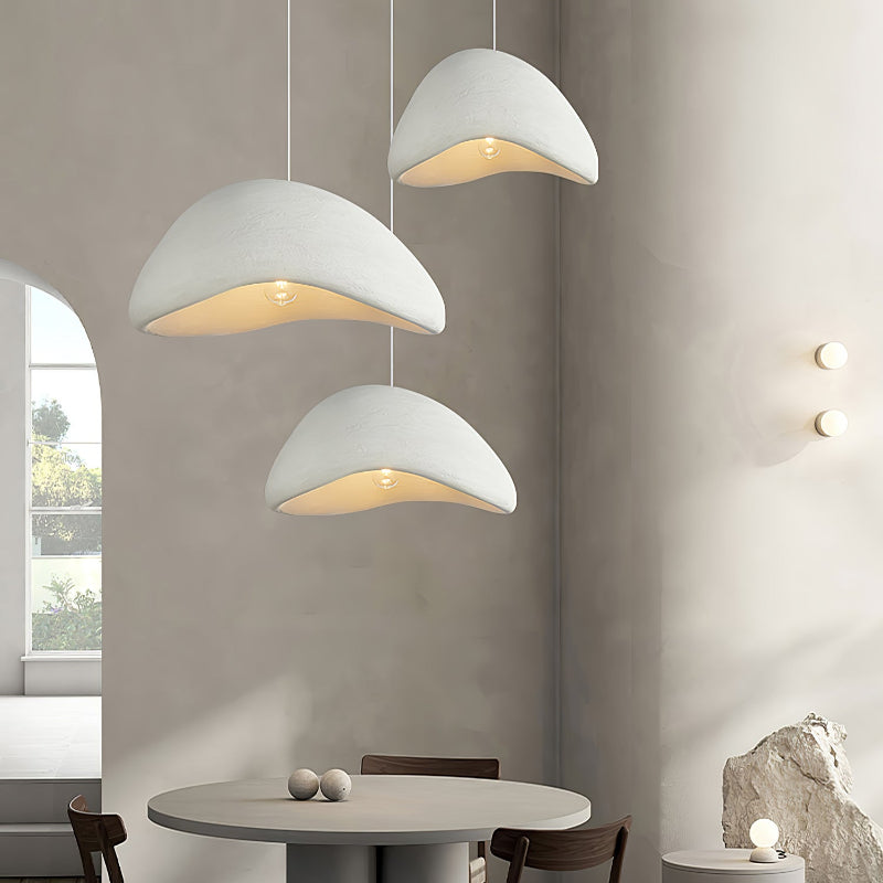 Group of three White textured cloud pendants above a round table in an interior with an arched window