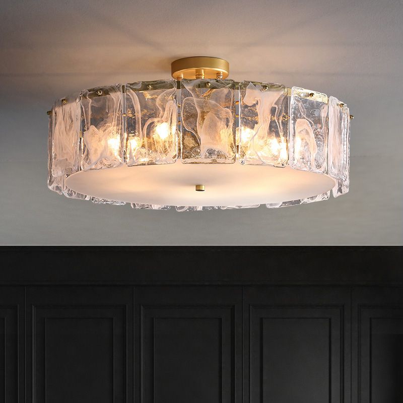 Wide Kirsten glass-panel light with a short gold-toned stem and pale bottom plate, above a dark panelled wall.
