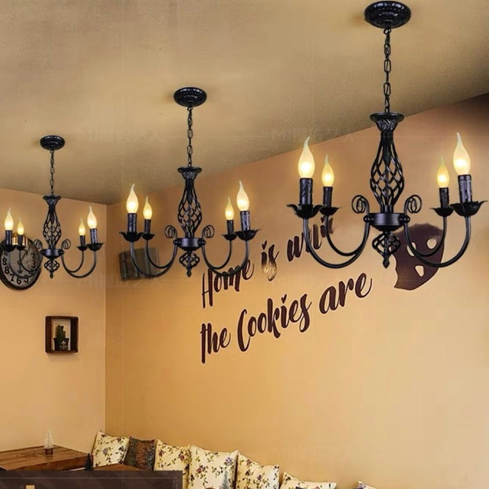 Row of black Silva four-light chandeliers above upholstered seating, decorative wall lettering and clock in warm interior