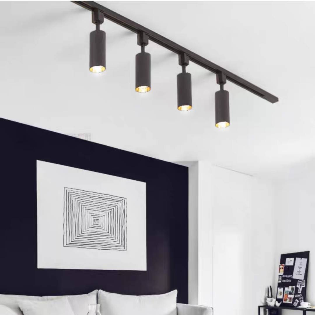 Black Freja four-head track above a pale sofa and concentric-square artwork against a dark feature wall.