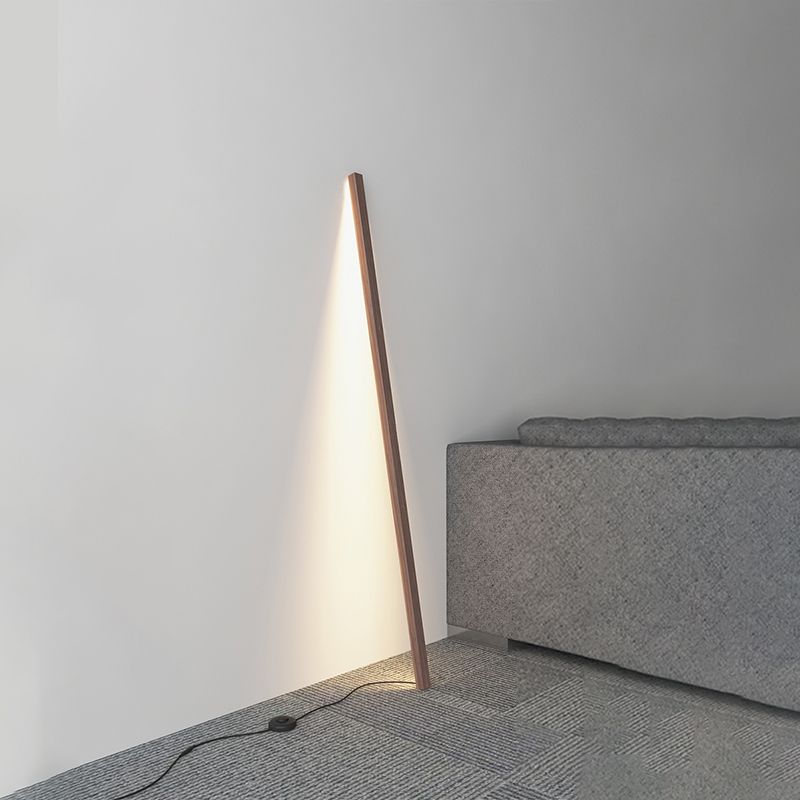 Dark wood light bar leaning by a gray sofa above a patterned carpet, with black cable and round floor control