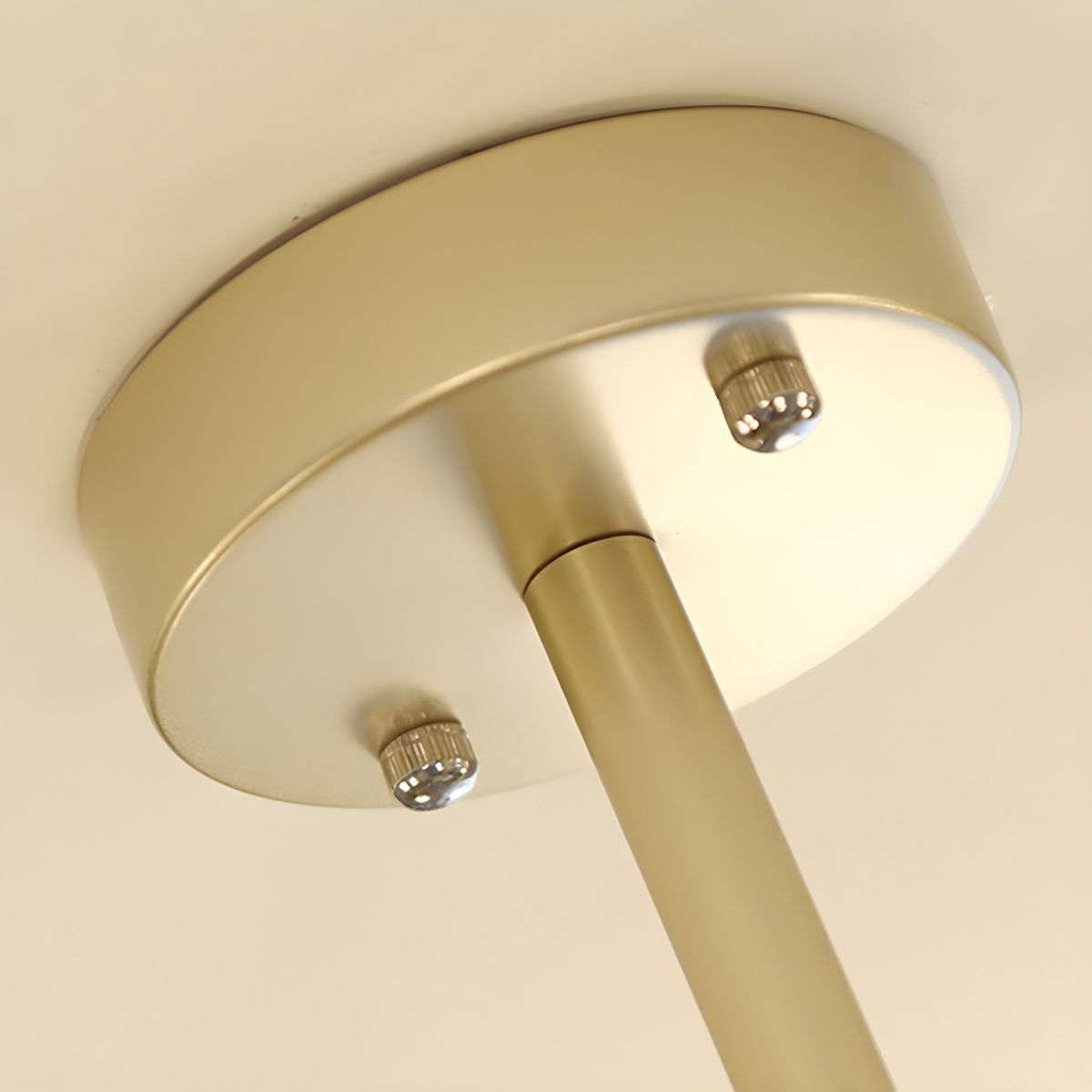 Close-up of the gold round ceiling canopy, two silver-toned knurled fasteners and the central metal stem