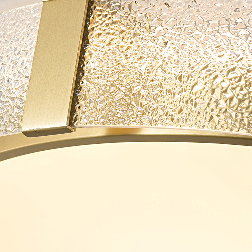 Close-up of a gold-tone support strip, irregular textured glass outer band and pale diffuser edge with gold-tone trim.