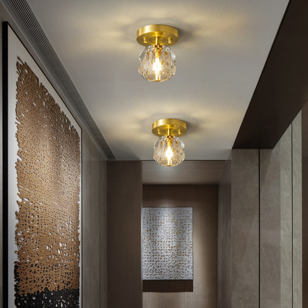 Two Kirsten ceiling fixtures in a grey-brown hallway above large gold leaf-pattern art, with mosaic art further along.
