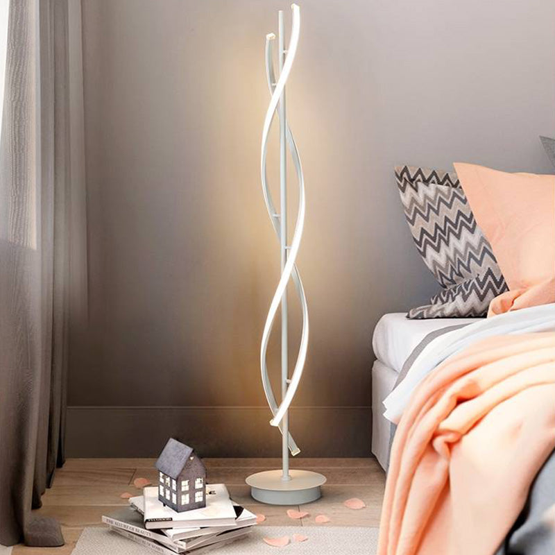 White Louise floor lamp beside a bed with a peach blanket, chevron cushion and books on the floor