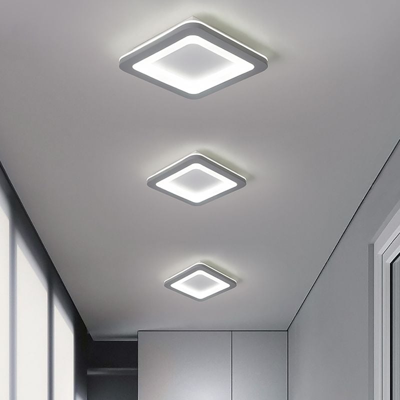 Three rounded square gray ceiling lights with white-lit outlines along a hallway