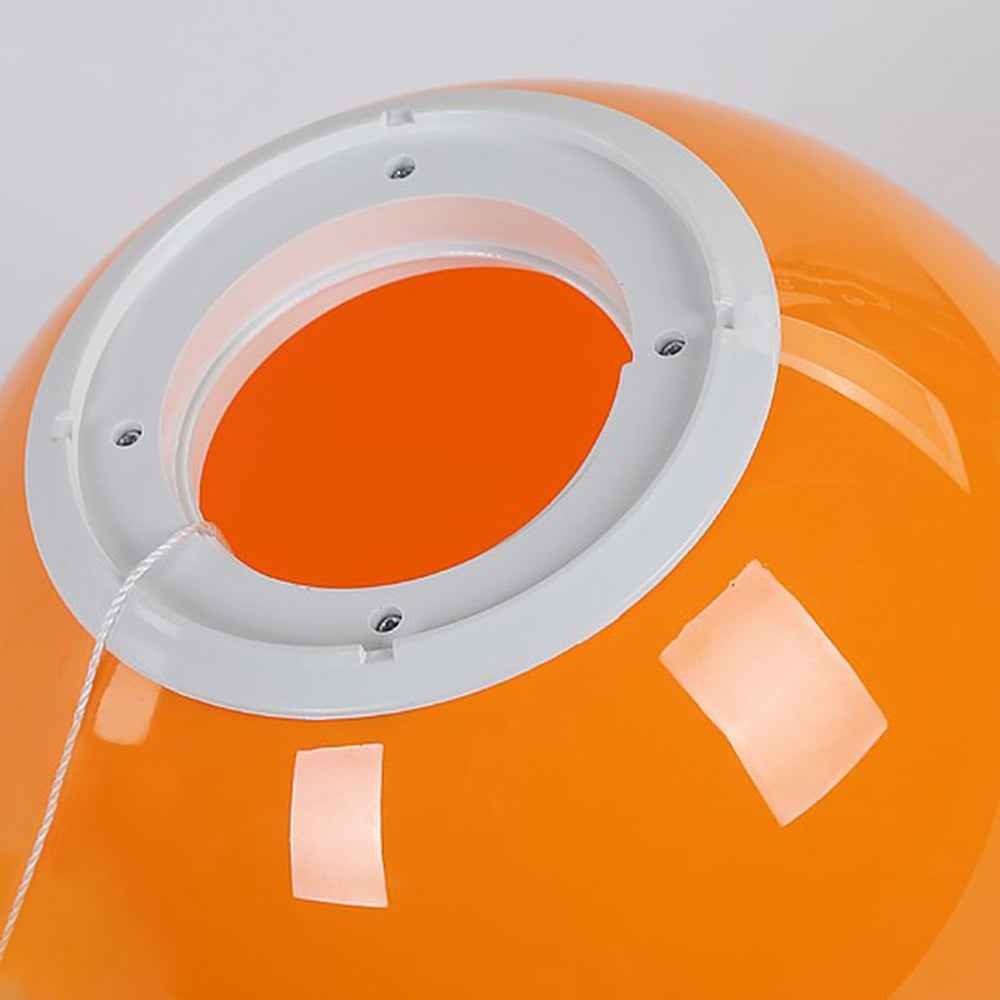 Rear opening of glossy orange Fateh with a pale circular mounting ring, four screw heads and a string passing through a side notch.