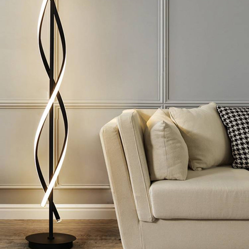 Close view of the lower black curved light strips and round base beside a beige sofa and paneled wall