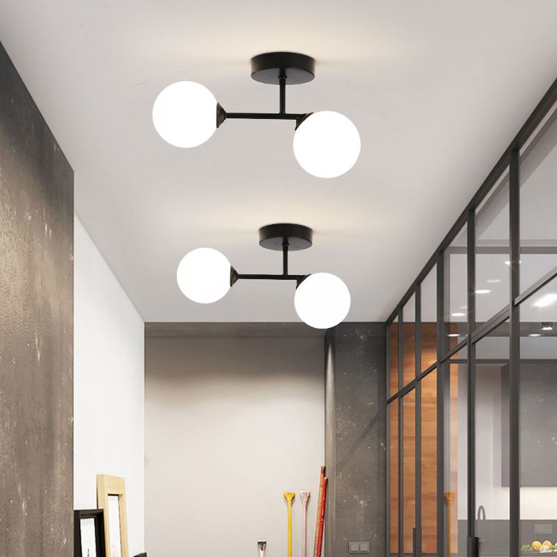 Two black Valentina fittings along an indoor ceiling beside a dark-framed glass partition and leaning picture frames.