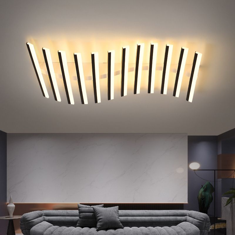 Quinn staggered light bars above a rounded gray sofa and broad pale wall panel, with separate room lighting and a green plant.