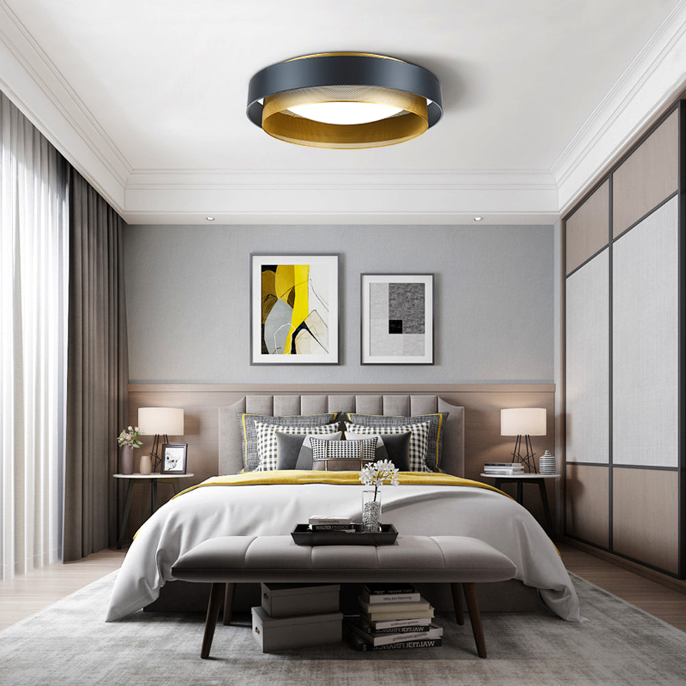 Black-and-gold Quinn ring light over a grey headboard, patterned pillows, yellow accents, bedside lamps and upholstered bench.