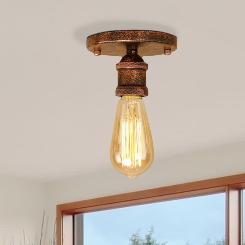 Rust-tone textured Alessio canopy and knurled holder above a glowing elongated bulb beside a wood window frame and blue sky.