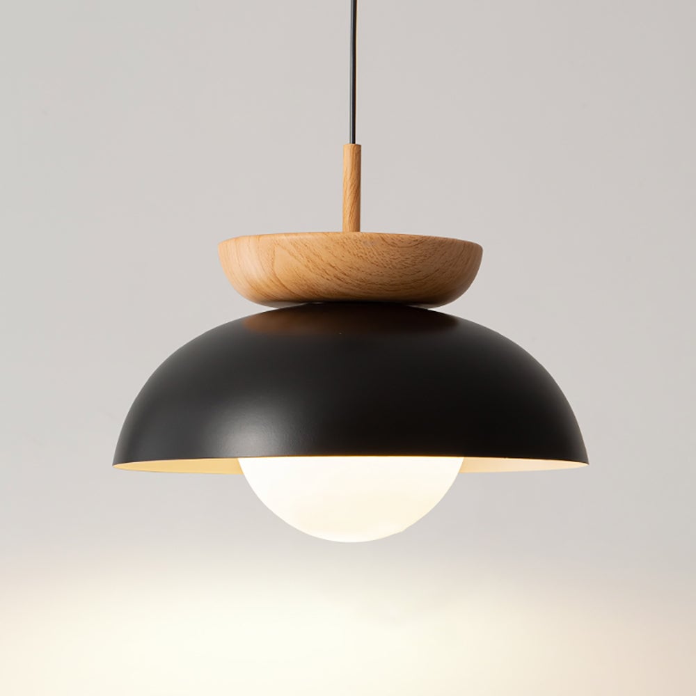 Close view of lit black dome pendant with wood-grain crown, black cord and white globe below the rim