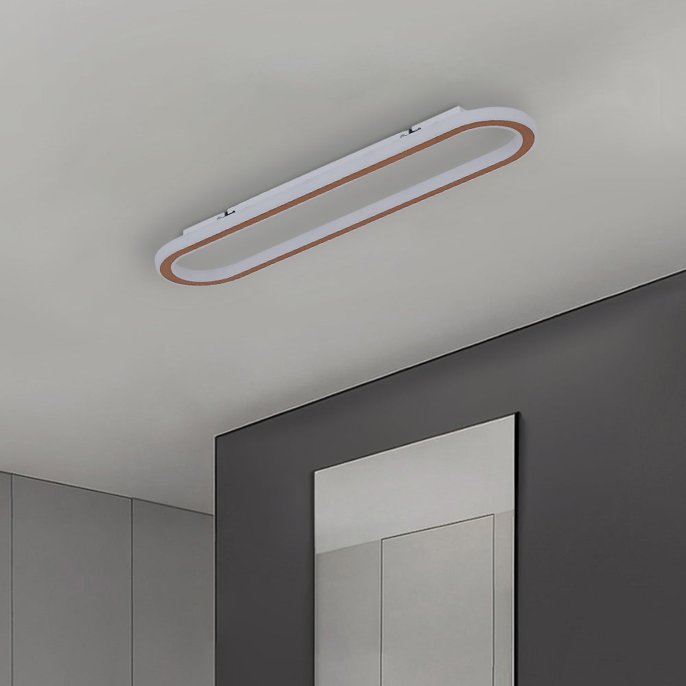 Unlit-looking Rose Gold Quinn fixture on grey ceiling above framed line artwork, with visible mounting strips.