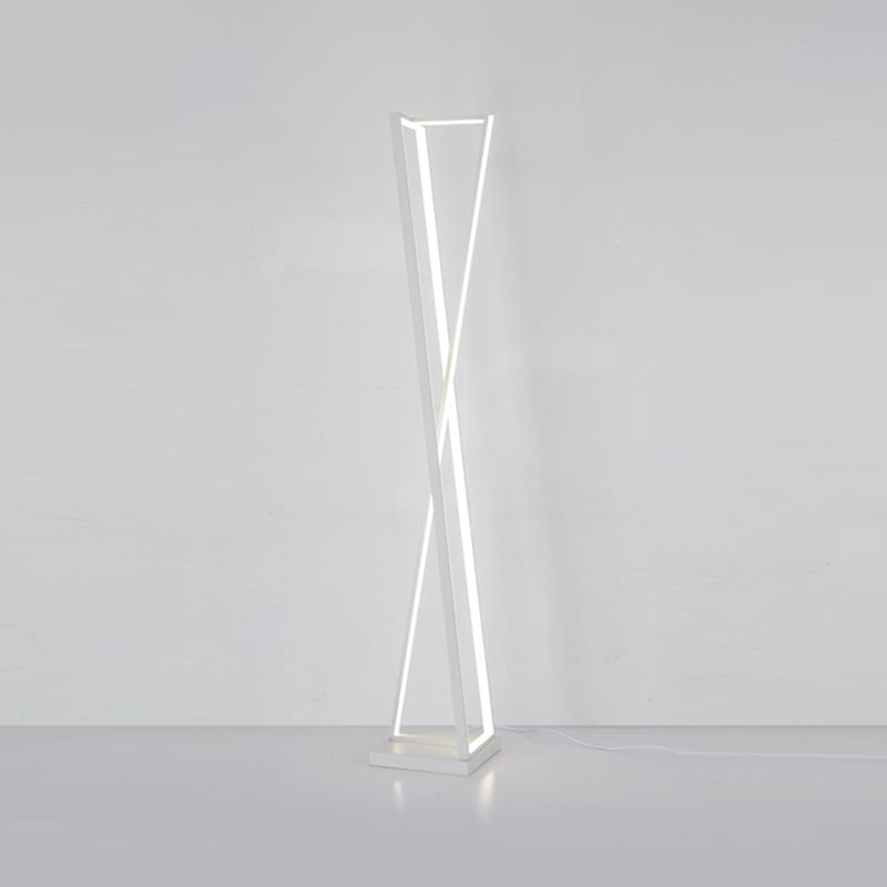 White crossed-triangle floor lamp with bright linear strips against a grey wall and floor, with cable trailing right