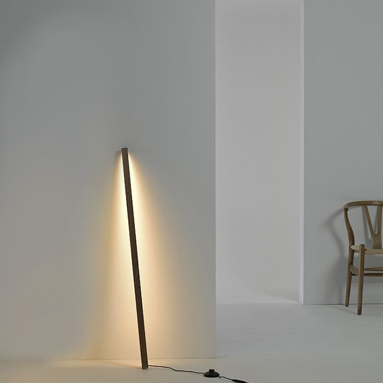 Dark wood-tone bar leaning against a wall with warm light, a black floor control and a wooden chair nearby