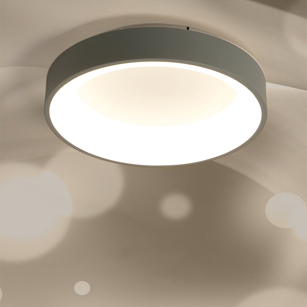 Oblique grey Quinn ceiling light on pale ceiling with warm-looking center and a lighter luminous inner ring.